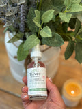Hand holding a bottle of Tilvee skincare product with plants and a candle in the background. soothing hydrosol toner that is hydrating and healing. Great for after sun, wind exposure, facials, microneedling and every day use. Sourced from fresh grown and distilled botanicals. 