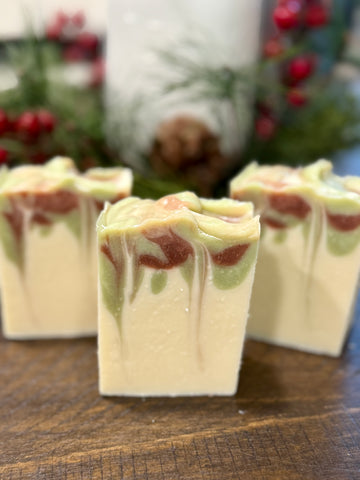 Decorative soap bars with red and green swirls on a wooden surface with a festive background.